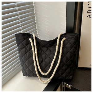 Détail du sac fourre-tout matelassé noir avec anses en corde blanche et motif losanges