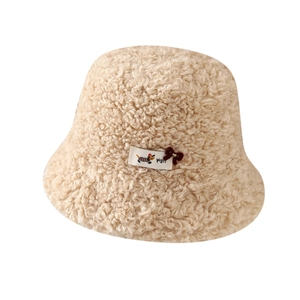 Beige faux shearling trapper hat with cartoon puppy patch and bow detail on white background