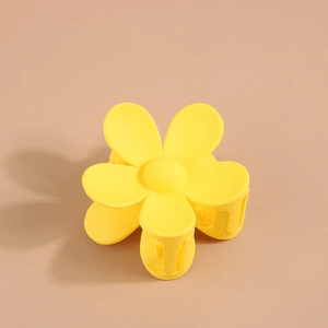 Détail d'une pince à cheveux fleur jaune mat avec cinq pétales et ressort de fixation