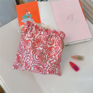 Close-up of drawstring pouch with red floral pattern and off-white cotton cord
