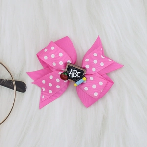 Detail of pink polka dot hair bow with school themes like chalkboard and apple