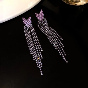 Detail view of purple rhinestone tassel earrings with V-shape design on dark surface