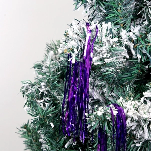 Close-up of purple tinsel garland hanging on a snow-flocked Christmas tree branch