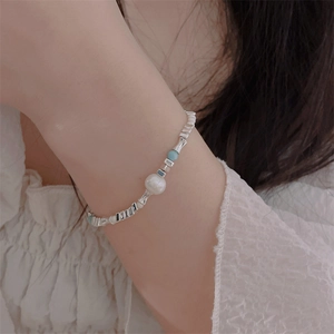 Close-up of a silver-toned beaded heart bracelet with white pearls and blue accents