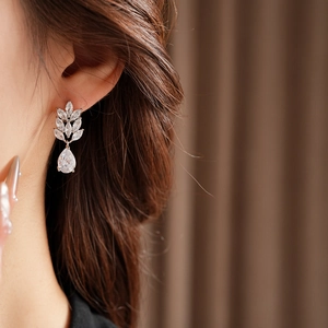 Close-up of elegant zircon leaf and waterdrop pendant earrings worn by a model