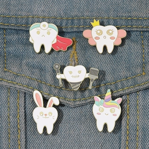 Gros plan de cinq épingles en émail de dents de dessin animé sur tissu en jean bleu