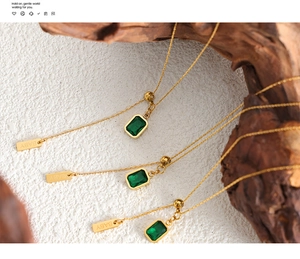 Detail of emerald zircon pendant with BABY letter bar on a gold titanium steel necklace