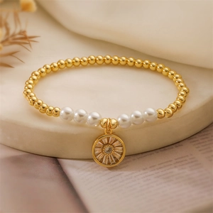 Détail d'un bracelet en perles dorées avec perles et pendentif soleil brillant en zircon