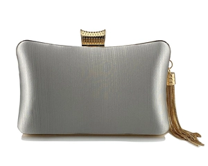 Macro detail of silver evening clutch with gold textured clasp and metallic tassels