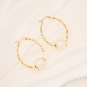 Detail of elegant gold stainless steel hoop earring featuring a large lustrous white pearl