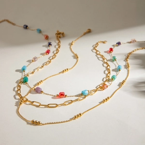 Detailed view of layered gold-tone necklace with colorful beads and paperclip chain