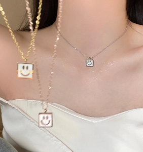 Detail of square smiley face pendant necklace in gold, silver and rose gold finishes