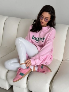Detail view of pink oversize sweatshirt with green legacy letter print on chest