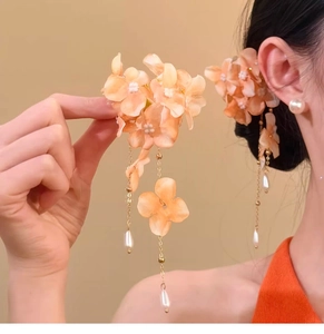 Detailed macro view of elegant fabric petal hair clip with long gold tassel and pearls