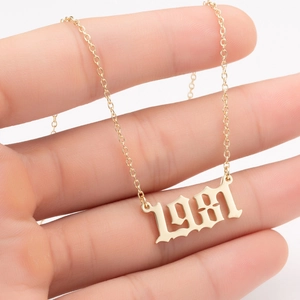 Detail of gold birth year 1981 pendant necklace with fine curb chain on hand