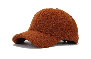 Close-up of caramel lamb wool texture on a winter baseball cap with soft plush fabric