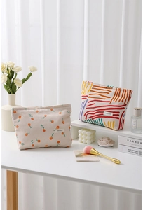 Detail of floral and striped corduroy cosmetic bags with H&R brand label on a desk
