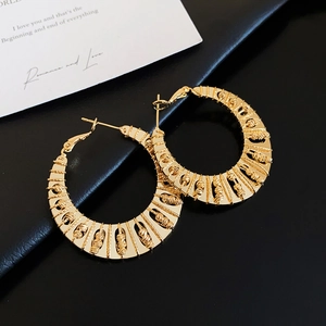 Close-up of gold plated twisted hoop earrings with textured vintage weaving design