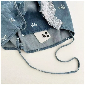 Close-up of denim tote bag with white bow print, lace trim and interior storage detail