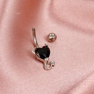 Macro shot of silver devil heart belly button ring with black gem on pink silk