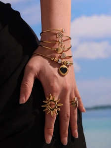 Parure de bijoux dorés bohème avec breloques cœur et bague soleil sur la plage