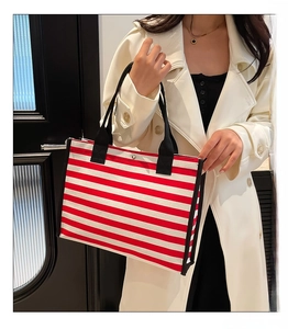 Detail view of large canvas tote bag with red and white stripes and black handles