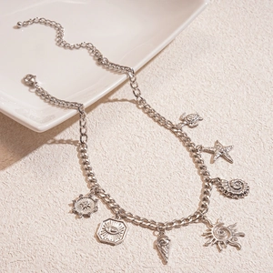 Dettaglio di una collana a catena barbazzale argento con sette ciondoli boho e moschettone