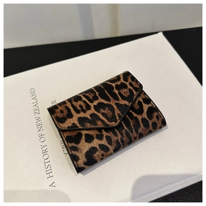 Dettaglio di un mini portafoglio chic con stampa leopardata su un libro in stile retrò