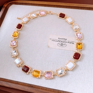 Detail view of vintage gold necklace with multi-colored square gemstones and ornate texture