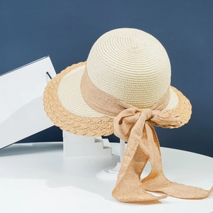 Detail of wide-brim straw hat with a large brown bow and decorative wavy edge design