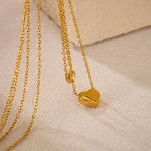 Detailed close-up of golden heart pendant with small zircon on stone background
