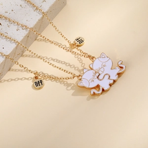 Detail of best friend gold cat necklaces with BFF tags on textured stone display