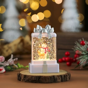 Close-up of lighted Christmas snow globe gift box with snowman and elk on wood base