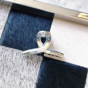 Detail of a silver metallic hair claw with a twisted ribbon design on a checkered rug