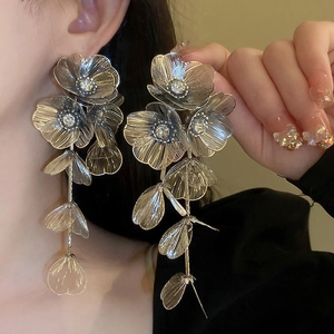 Detail of silver hollow flower tassel earrings on model showing long layered petals