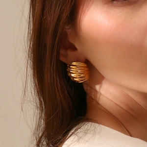 Vue détaillée de grandes boucles d'oreilles nœud texturées plaquées or 18K sur un mannequin