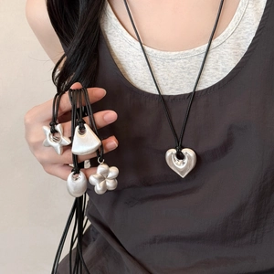 Close-up of minimalist matte silver pendants in heart and star shapes on black cords