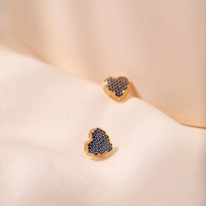 Macro view of gold plated heart stud earrings with pave set blue zircon crystals