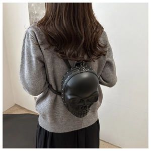 Detail of black PU leather skull backpack with decorative rivets worn by a model