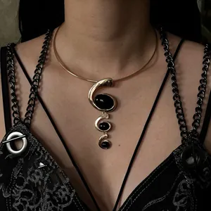 Detail of gothic gold collar necklace featuring triple black oval resin pendants