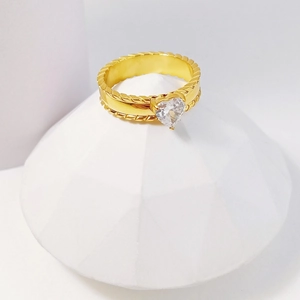 Elegant gold titanium ring with a heart-shaped zircon stone on a white geometric stand