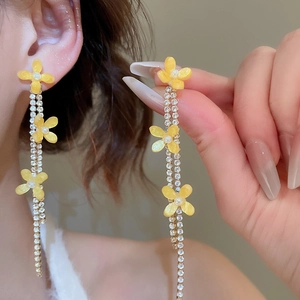 Detail of yellow flower earrings with resin petals, pearls and sparkling rhinestone tassels
