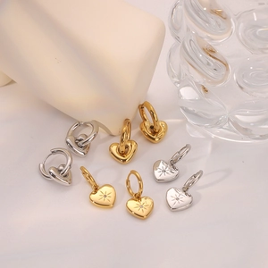 14k gold and silver heart hoop earrings with sparkling zircon accents on white fabric