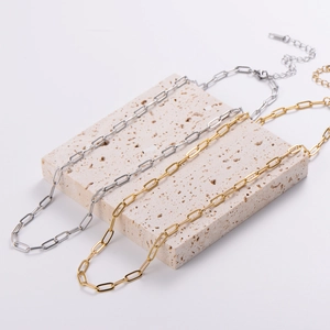 Minimalist gold and silver stainless steel paperclip chain necklaces on stone display