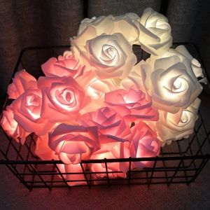 Close-up of pink and white foam LED rose string lights glowing in a black wire basket