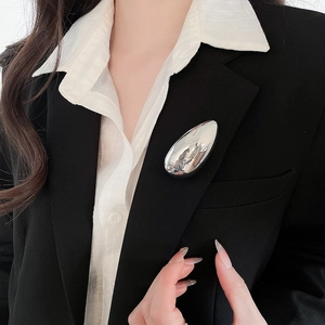 Minimalist silver water drop brooch pinned on a black suit jacket lapel for a professional look