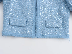 Close-up of light blue tweed jacket hem featuring white sequins and fringe details