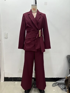Detail of burgundy blazer suit featuring unique waist buckle and tailored trousers