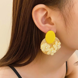 Model wearing large vintage earrings with yellow disk and white fabric flowers