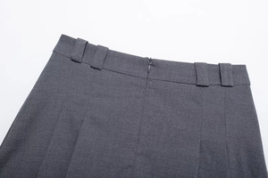 Detail of dark gray pleated skirt waist featuring belt loops and invisible zipper closure